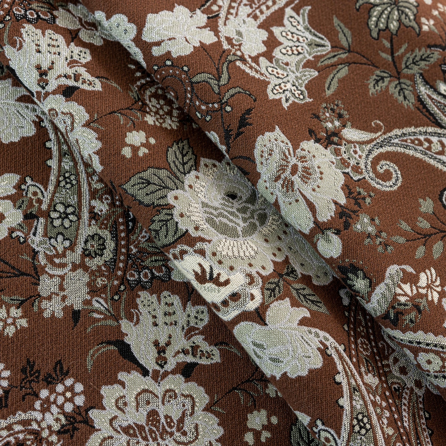 Close-up of retro floral and paisley patterned curtain fabric, highlighting detailed textures and vintage design.