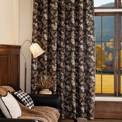 Floral patterned curtains in a room with a lamp and window view.