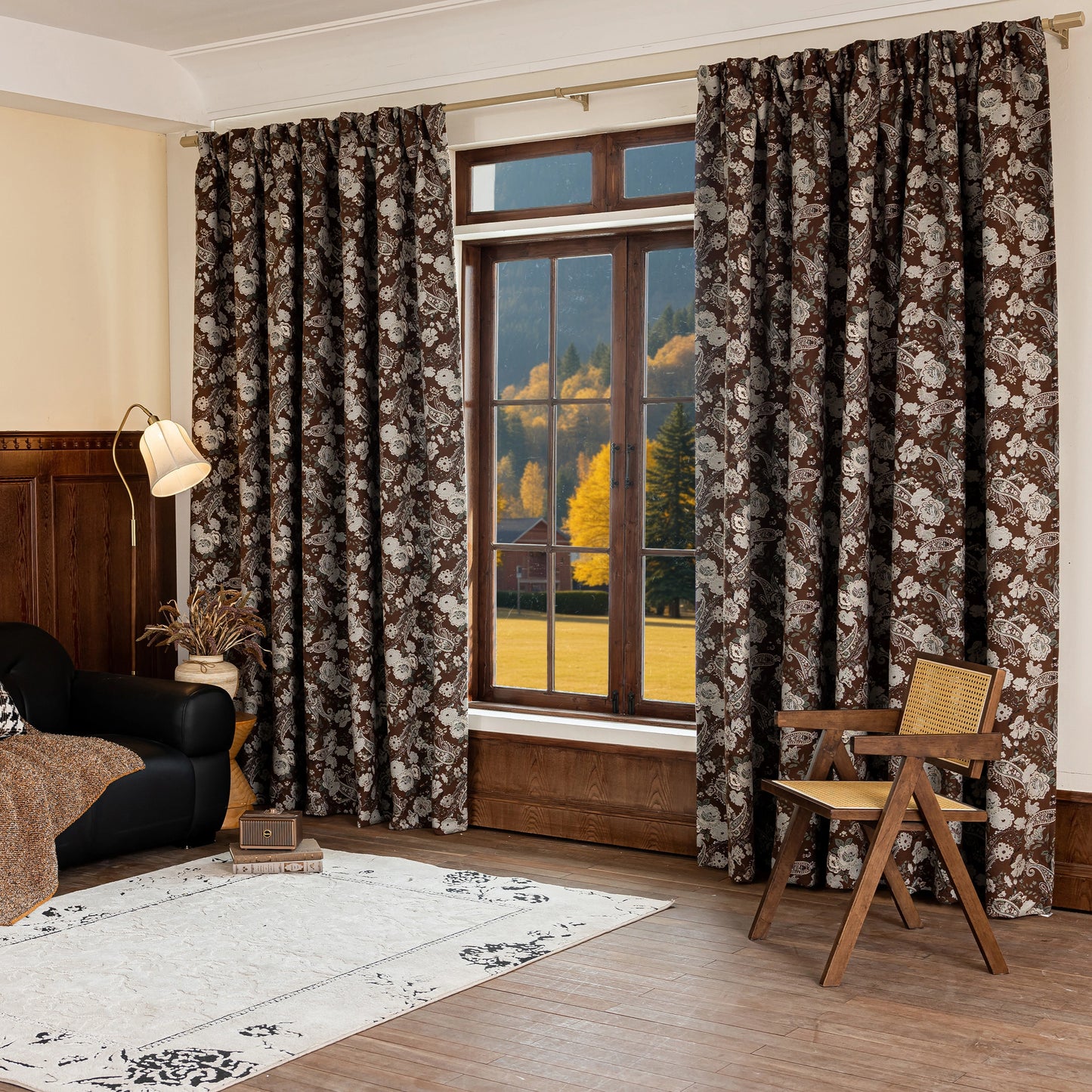 Large window framed with antique-style floral curtains, with a rug, chair, and lamp in the room.