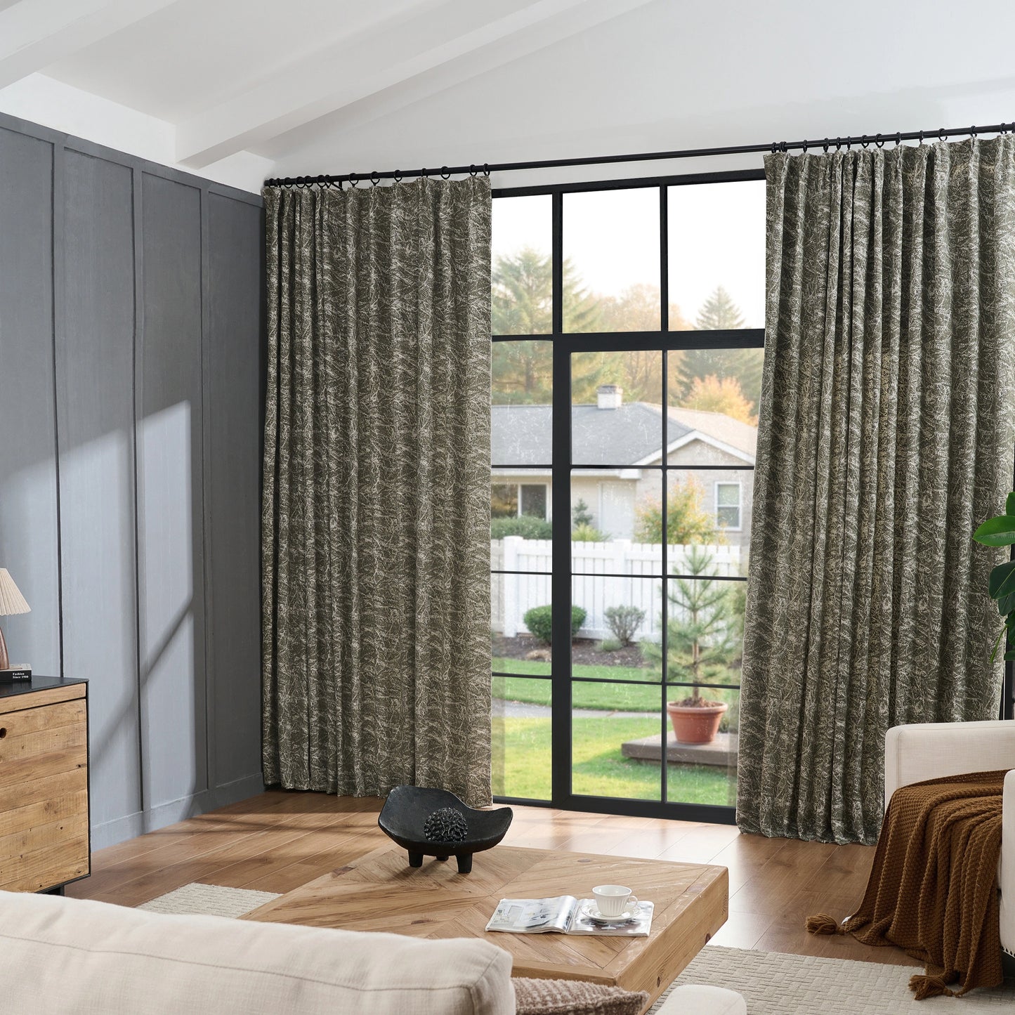 Living room with vintage jade curtains in sketched line pattern, wooden table and sofa placed in front.