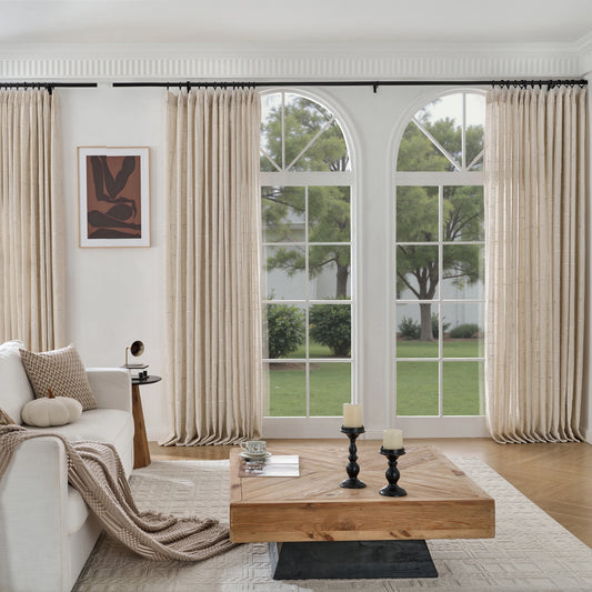 Living room with a wooden table, sofa, and large windows with ecru wool–poly blend curtain with tactile raised pattern.